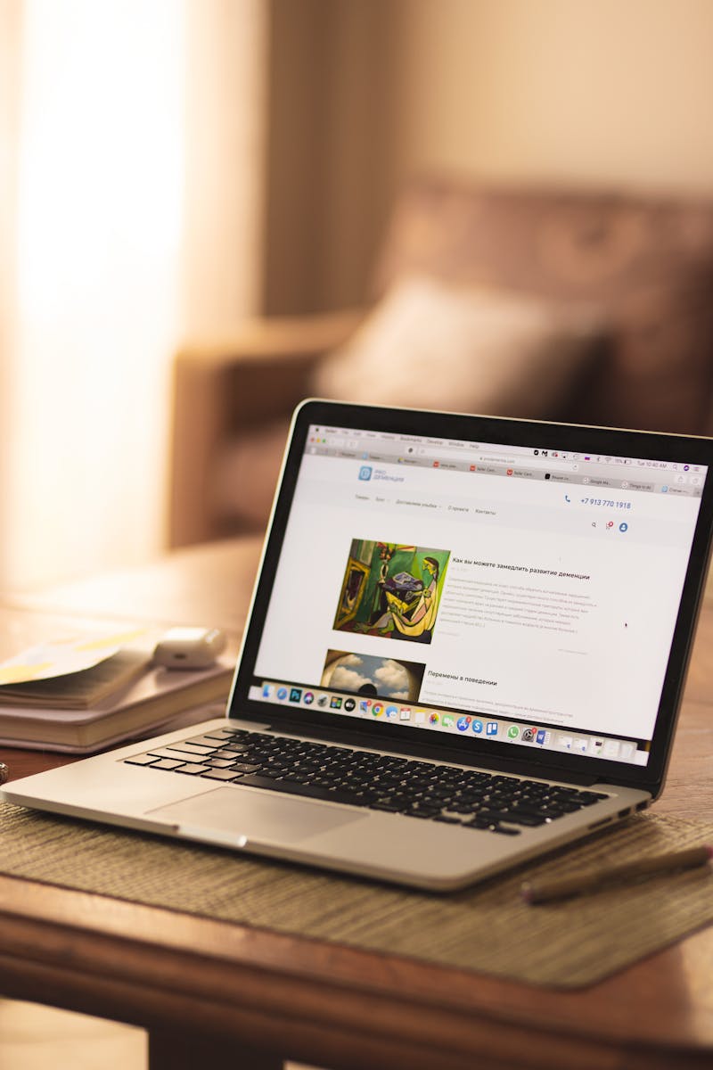 A cozy indoor workspace featuring an open laptop on a wooden table with soft lighting.